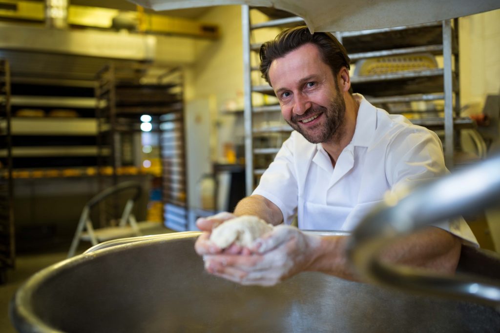 smiling-baker-preparing-dough Baker preparing dough